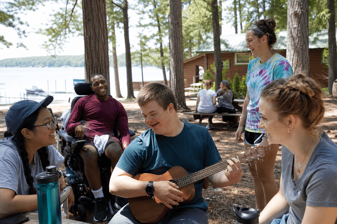 Inclusive summer camp group gathered on a wooden dock by a lake