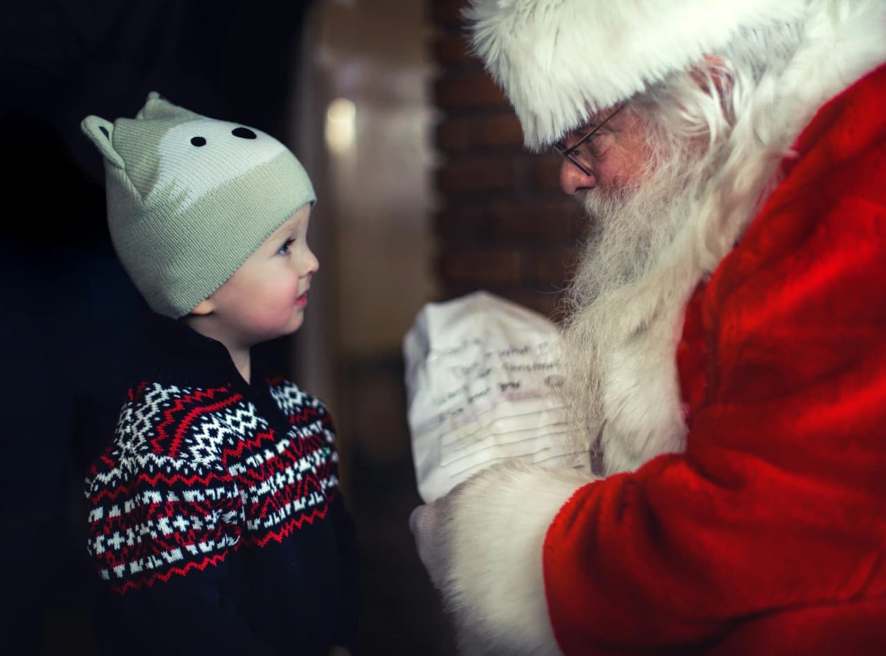 Young child looking up at Santa Claus during a home visit